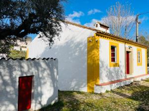 una pequeña casa blanca y amarilla con puerta roja en Casa do Martinho, en Castelo de Vide