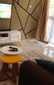 a living room with a table and a stool and a tv at Brooks apartments in Kampala