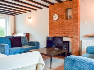 a living room with blue chairs and a fireplace at Sidelands Sojourn in Stratford-upon-Avon
