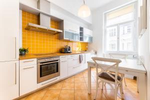 a kitchen with white cabinets and a table with a chair at Big bright two-bedroom apartment in Prague Old Town in Prague