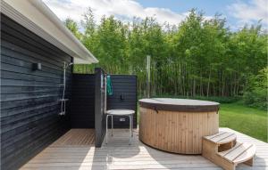 a wooden deck with a hot tub and a chair at Holiday Home Toftegårdsvej Hasle X in Tofte