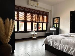 1 dormitorio con cama, ventanas y mesa en SID house en Ban Hua Laem Ma So