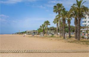 une plage de sable avec des palmiers et un bâtiment dans l'établissement Gorgeous Apartment In Malgrat De Mar With Kitchenette, à Malgrat de Mar