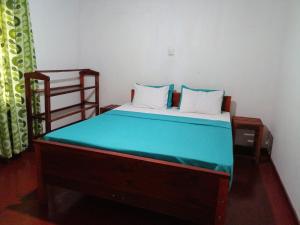 a small bedroom with a bed with a blue bedspread at Serenity Retreat Sinharaja in Deniyaya