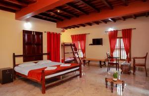 Cette chambre comprend un lit avec des rideaux rouges et une télévision. dans l'établissement Kudajadri Heritage Homestay, à Kaniyāmbetta