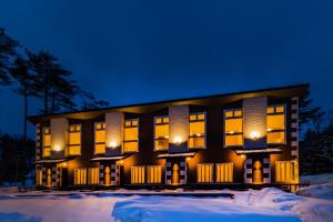 a building in the snow at night at HOPETREE CoCo HAPPO TOWNS in Hakuba