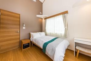 a small bedroom with a bed and a window at HOPETREE CoCo HAPPO TOWNS in Hakuba