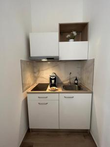 Una pequeña cocina con gabinetes blancos y un fregadero. en Fior di Loto Suite - Antonelli, en Turín