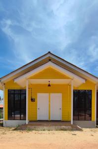 a yellow house with two white doors at A’Casa Cottage in Kuala Terengganu