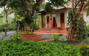 une maison avec un arbre et quelques buissons dans l'établissement Kudajadri Heritage Homestay, à Kaniyāmbetta