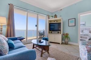 a living room with a blue couch and a tv at Ocean Villa Penthouse #2302 in Panama City Beach