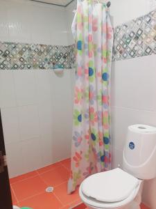 y baño con aseo y cortina de ducha. en Habitaciones Isa; lugar para tu descanso, en Armenia