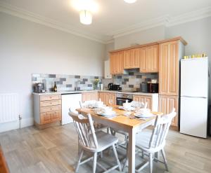 a kitchen with a wooden table and a white refrigerator at Woodside Oak hot tub & pool sleeps 4-6 in Bideford