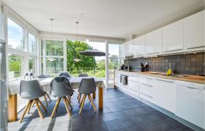 uma cozinha com armários brancos e uma mesa com cadeiras em Coras Hytter em Fårevejle