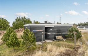 a small black building with a bench in a field at Holiday Home Grårisvej Thisted V in Nørre Vorupør