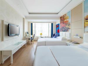 a hotel room with two beds and a flat screen tv at Lingshang Hotel in Yiwu