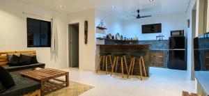 a kitchen with a bar with stools and a couch at Calao Villa, Solar Villa 2 rooms with Private Pool in El Nido