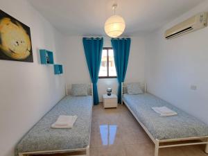 two beds in a room with blue curtains at Afroditi Apartment in Perivolia