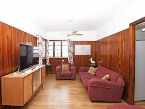 ein Wohnzimmer mit zwei lila Sofas und einem TV in der Unterkunft Family Tides in Urangan