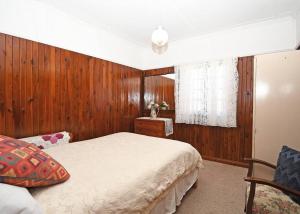 Schlafzimmer mit Holzwänden, einem Bett und einem Fenster in der Unterkunft Family Tides in Urangan