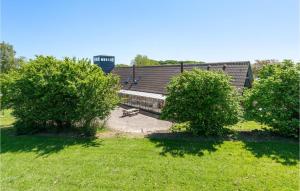 un bâtiment avec deux arbres et un banc dans un champ dans l'établissement Fuglsang, à Tranekær