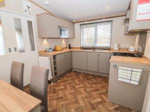 a kitchen with white cabinets and a wooden floor at La Hacendia Lodge in Morpeth