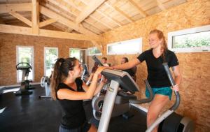 dwie kobiety ćwiczące na bieżni w siłowni w obiekcie Camping Officiel Siblu La Plage w mieście Mimizan