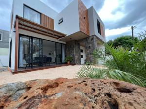 a house with a large rock in front of it at Into the Sun - Modern Holiday Home in Albion