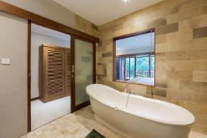 a large bathroom with a tub and a window at Alamdini Resort Ubud in Ubud