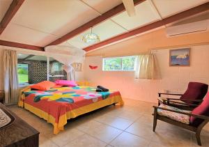 a bedroom with a large bed and a chair at Ann's Beach House in Rarotonga