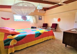 a bedroom with a colorful bed with two chairs and a window at Ann's Beach House in Rarotonga