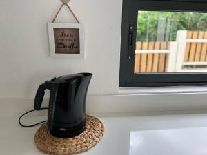 a coffee maker sitting on a coaster next to a window at Into the Sun - Modern Holiday Home in Albion