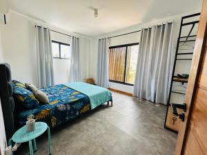 a bedroom with a bed and a table and windows at Into the Sun - Modern Holiday Home in Albion