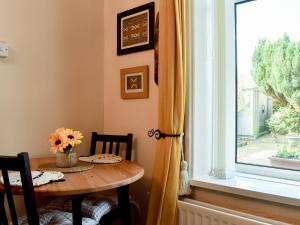 stół z wazonem kwiatów i oknem w obiekcie Ivy Cottage w mieście Newchurch