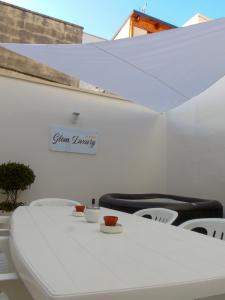 una mesa y sillas blancas con un cartel en la pared en Glem Luxury, en Copertino