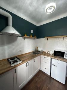 uma cozinha com armários brancos, um lavatório e um fogão em Апартаменти в центрі біля Либідь-Плази em Khmelnytskyi