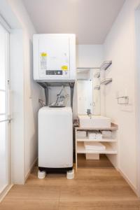 a small bathroom with a sink and a refrigerator at WHITE HAKUBA in Iida