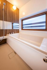 a white bathroom with a tub and a window at WHITE HAKUBA in Iida
