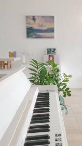 a white piano in a room with a plant at Najai Home Stay lamphun in Lamphun