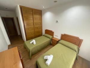 Una pequeña habitación con dos camas y una mesa. en Camiño Portugues, en Padrón