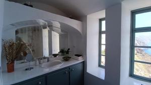 y baño con lavabo y espejo. en Elias Cave House 270o Caldera View Oia, en Oia