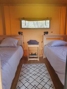 2 camas en una habitación pequeña con ventana en Luxury Safari Tents at Moulin Du Pommier Glamping & Camping, en Saulgond