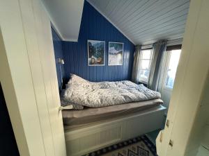 a small bedroom with blue walls and a bed at Lofotbua in Offersøya