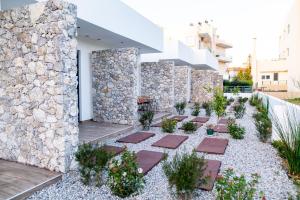 une cour avec un mur en pierre et quelques plantes dans l'établissement Pebble Garden Blue Dahlia, à Kos