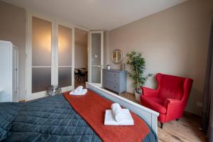 Un dormitorio con una silla roja y una cama con toallas. en New Town - Apple Apartments, en Praga