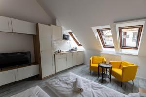 a room with two yellow chairs and a kitchen at Roomstore Studio Apartments in Eger