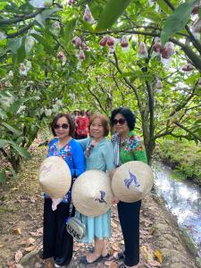 un gruppo di tre donne che tengono i piatti di Rooster Mekong Garden & Villas a Ben Tre