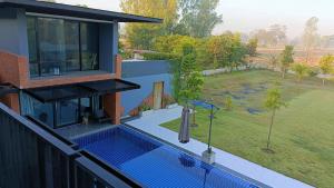 a house with a swimming pool next to a yard at Family Pool View บ้านพักครอบครัวและสระว่ายน้ำ in Ban Bu Lao