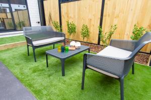 een patio met 2 stoelen, een tafel en een grill bij Stylish 2-Bedroom Haven Next to Hagley Park in Christchurch