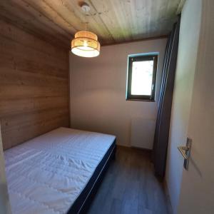 een slaapkamer met een bed in een kamer met een raam bij Cocon familial au pied des pistes in Morillon